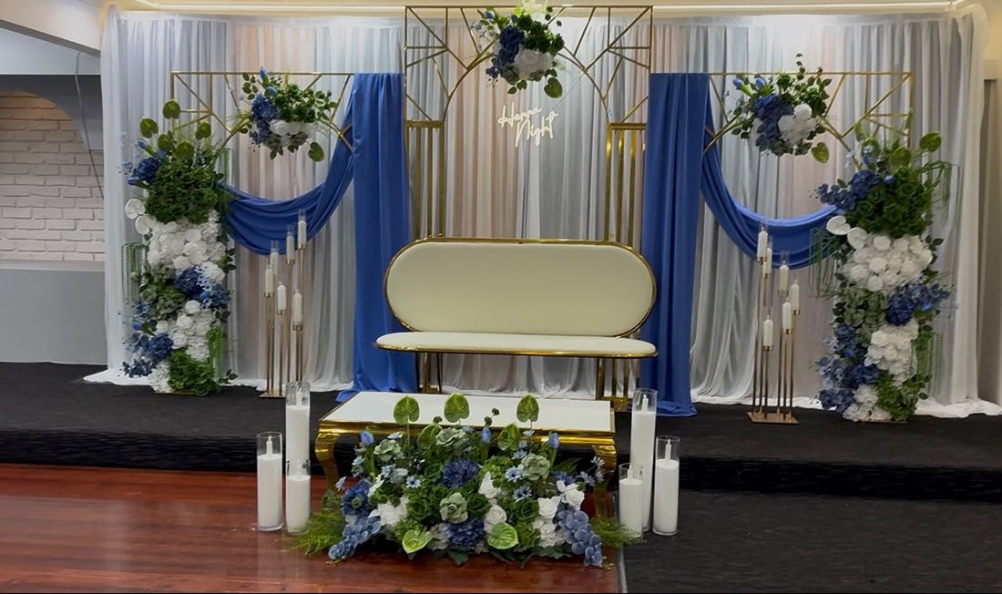Royal Blue and Gold Ceremonial Stage adorned with lush floral cascades and candle pillars